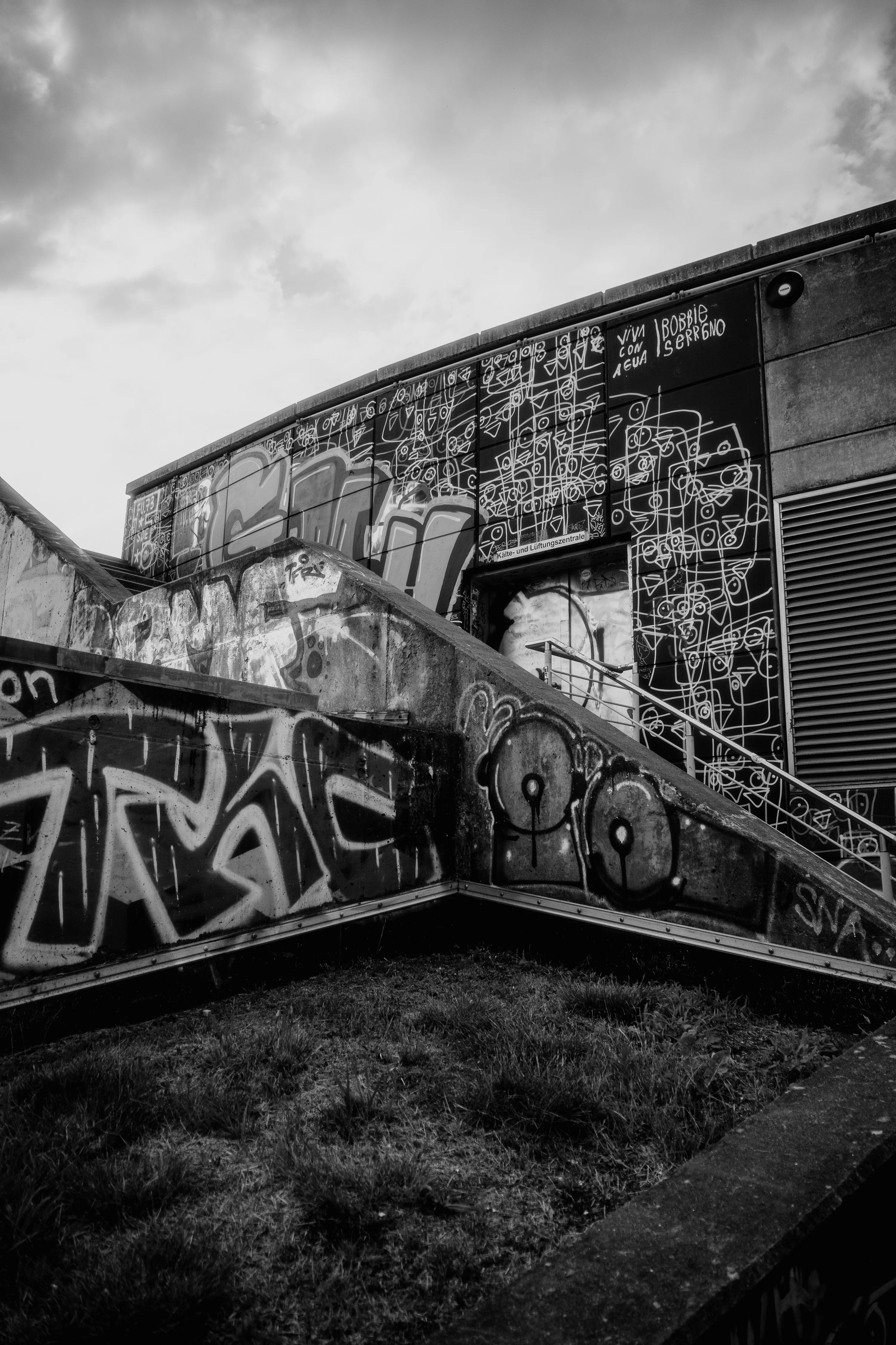 Black and white photo of a building wall covered in abstract graffiti art.