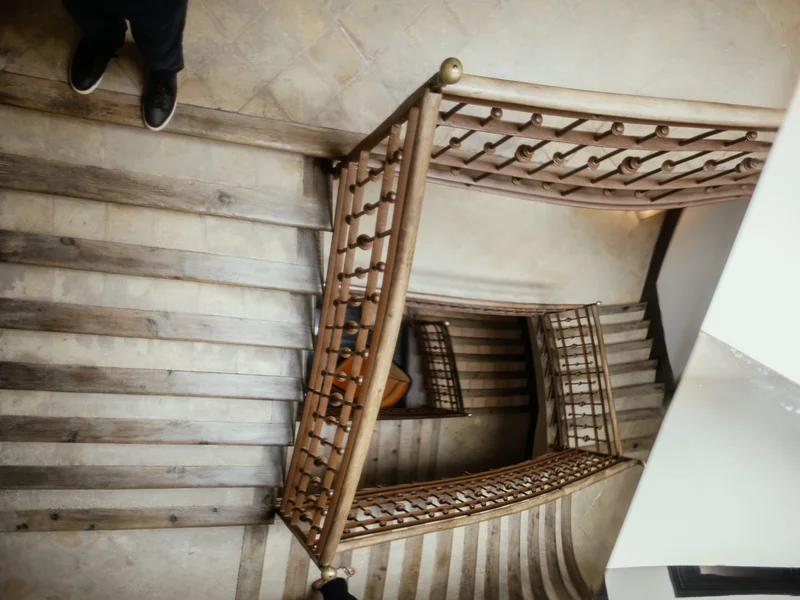 A spiral staircase viewed from above, showcasing multiple wooden steps and railings.