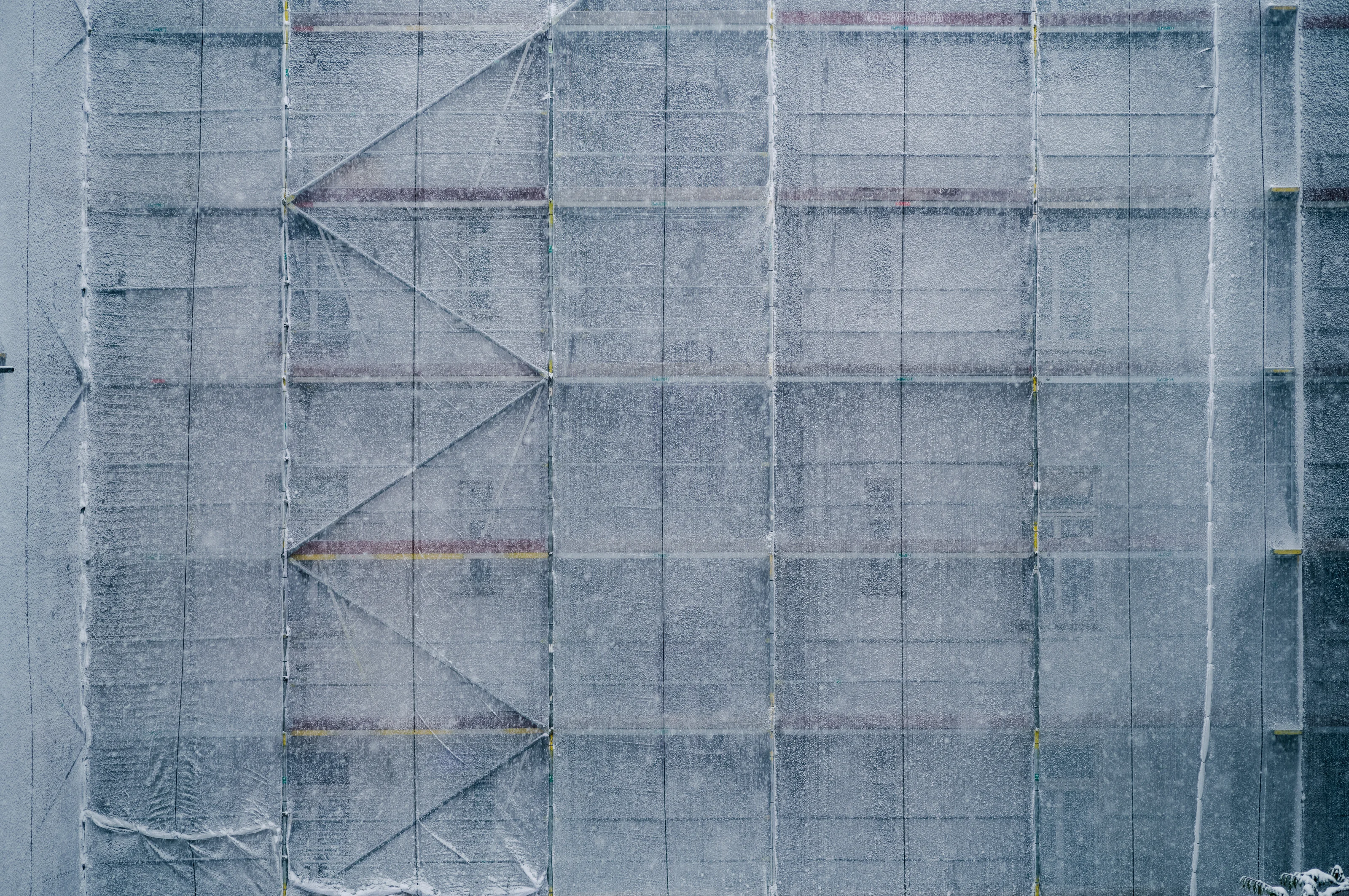 Scaffolding covered in protective netting with visible diagonal bracing patterns.