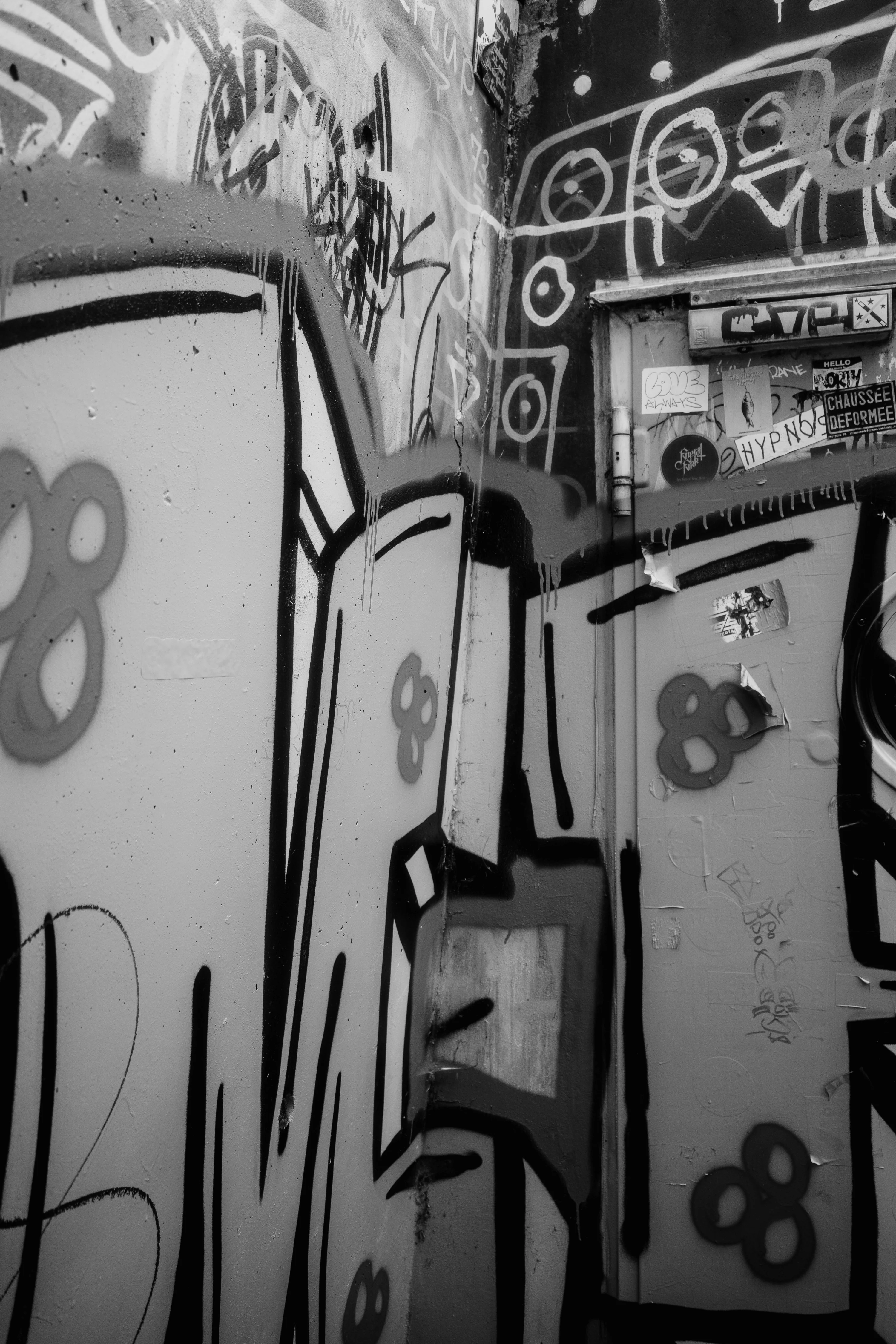 Black and white graffiti on a corner wall with abstract shapes and stickers.