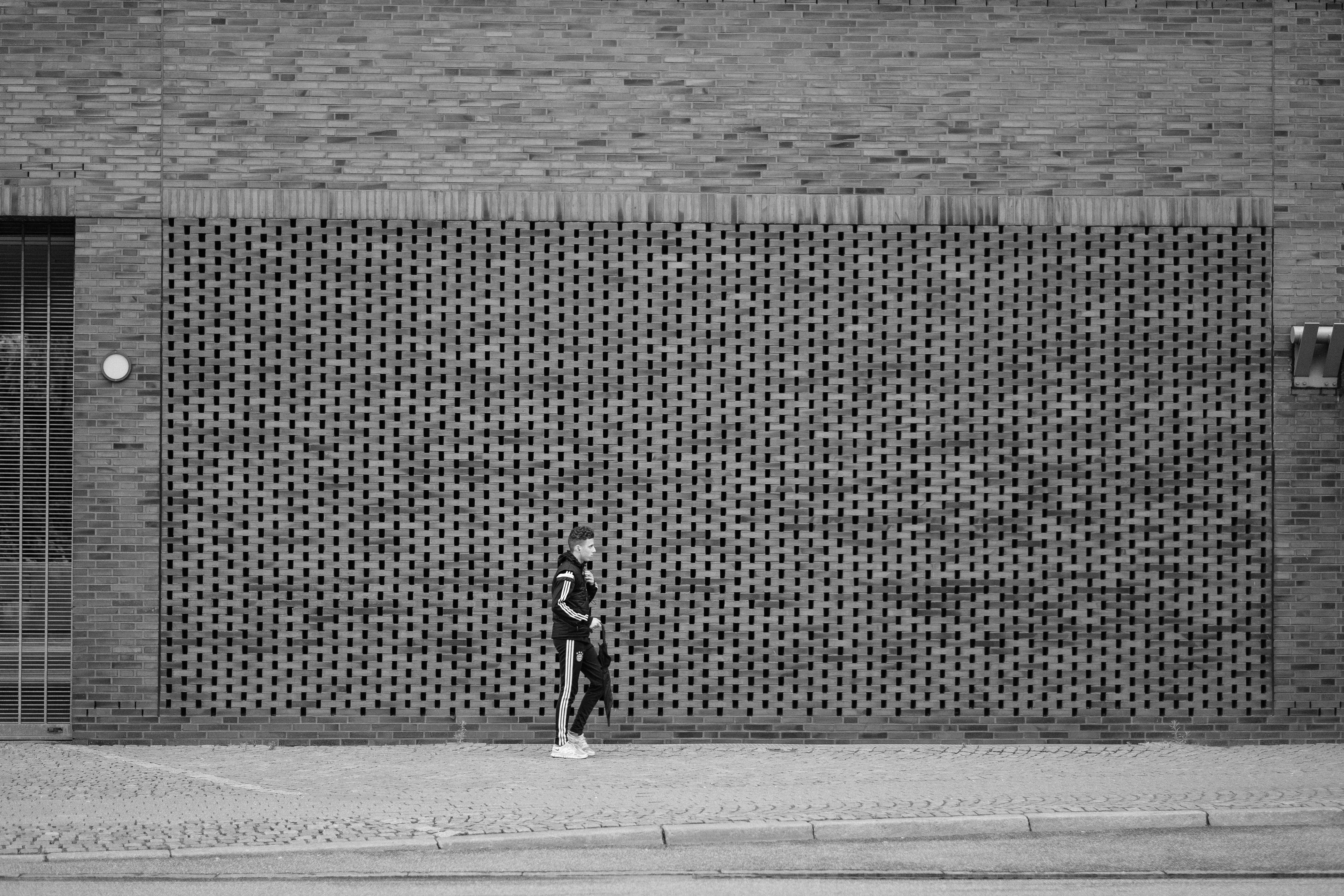 Person walking along a patterned brick wall.