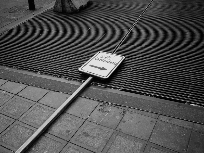 A fallen road sign with the word 'Omleiding' on a metal grate.