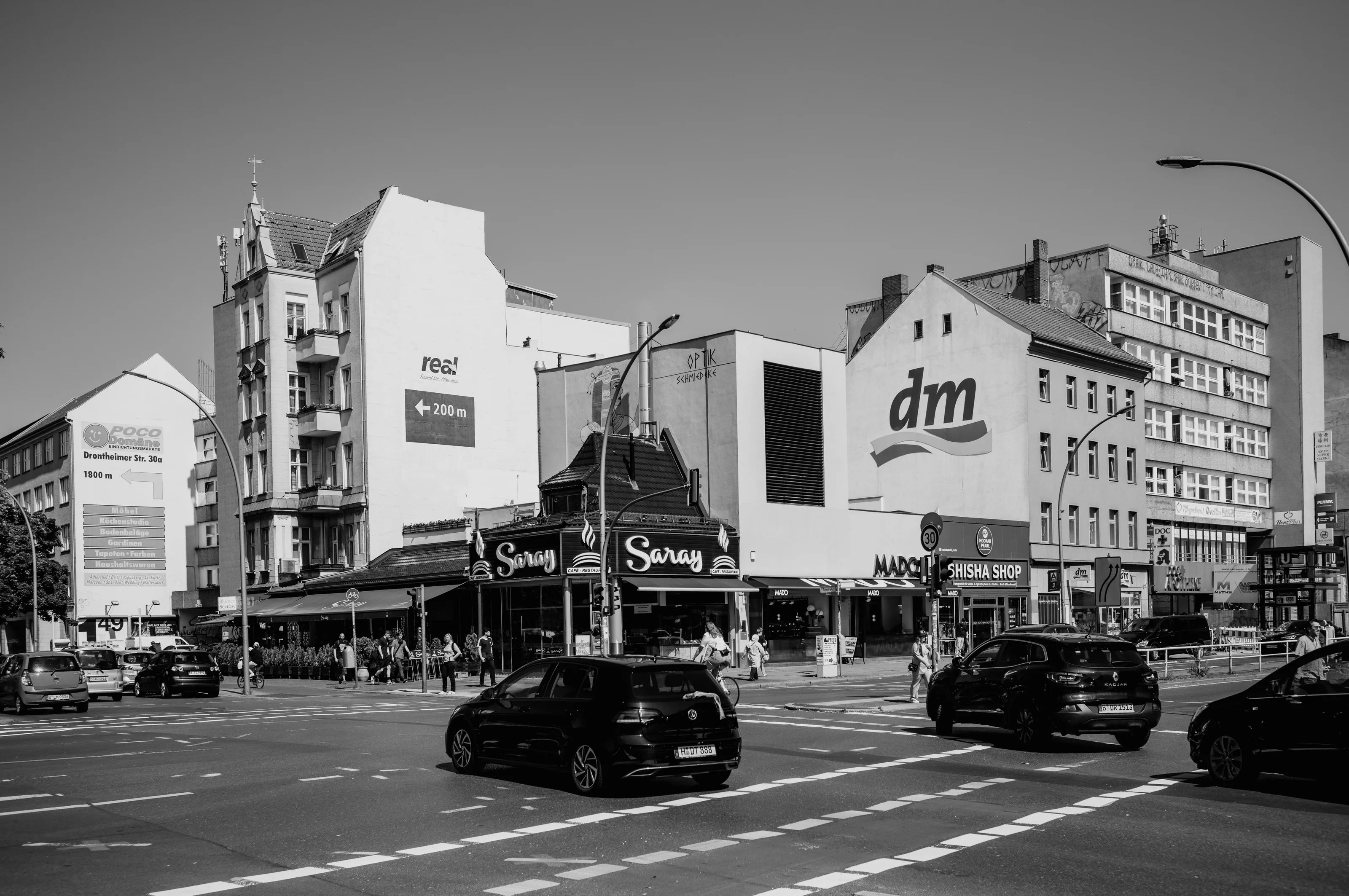 Urban street scene with cars and people in front of buildings featuring prominent logos.
