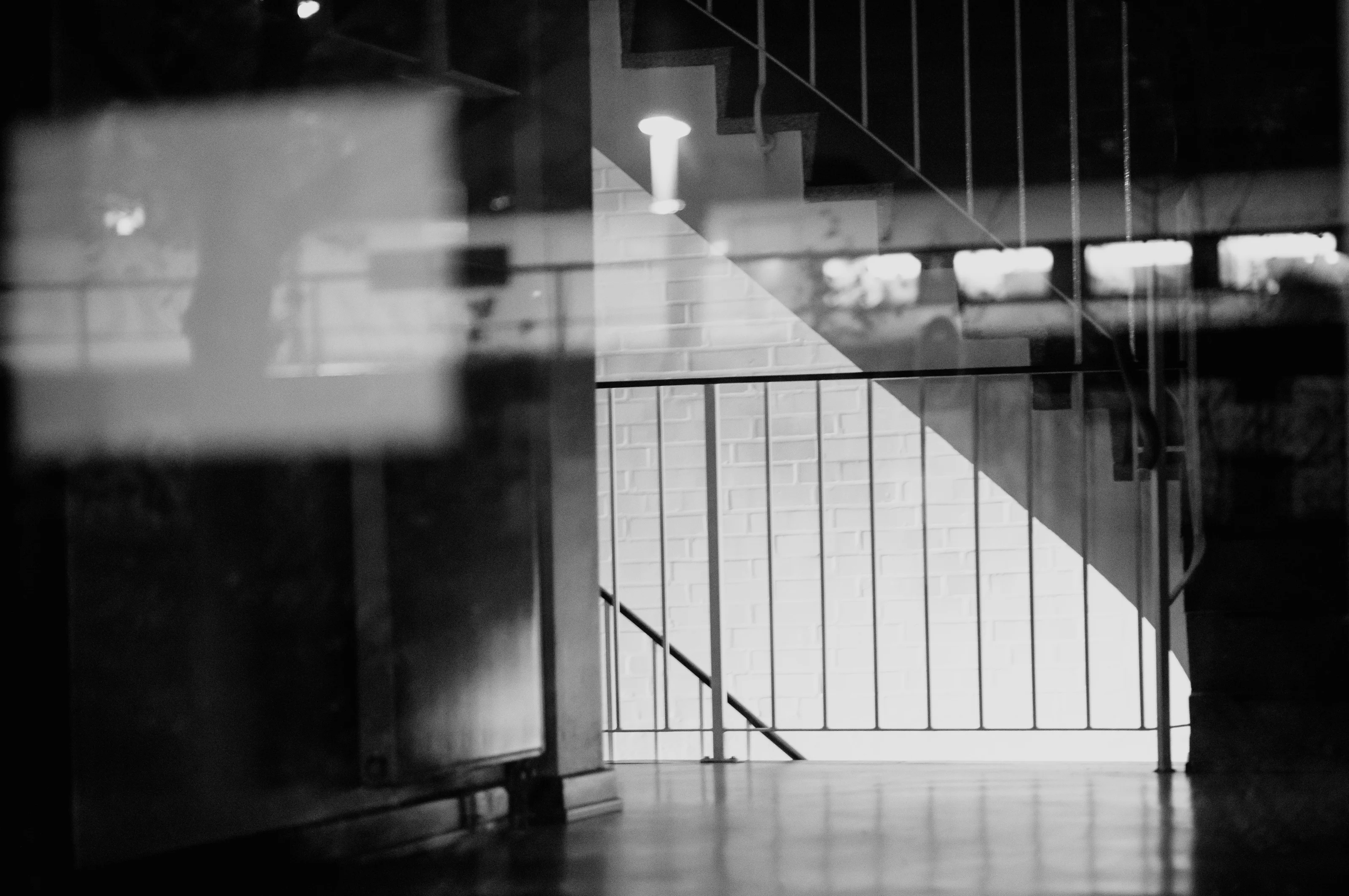 Abstract black and white photo of a staircase with a railing and soft reflections.