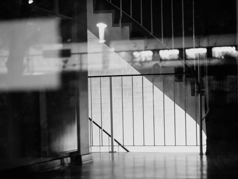 Abstract black and white photo of a staircase with a railing and soft reflections.