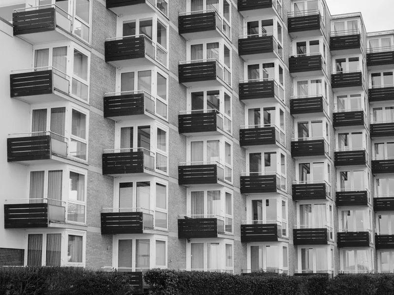 A black and white photo of a modern apartment building with multiple balconies.