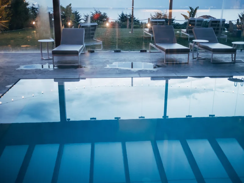 A serene outdoor pool area with lounge chairs overlooking the ocean.