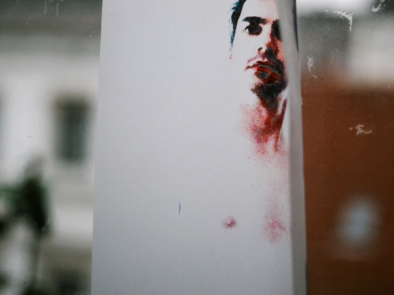 A photo of a printed portrait taped to a window with an urban backdrop.