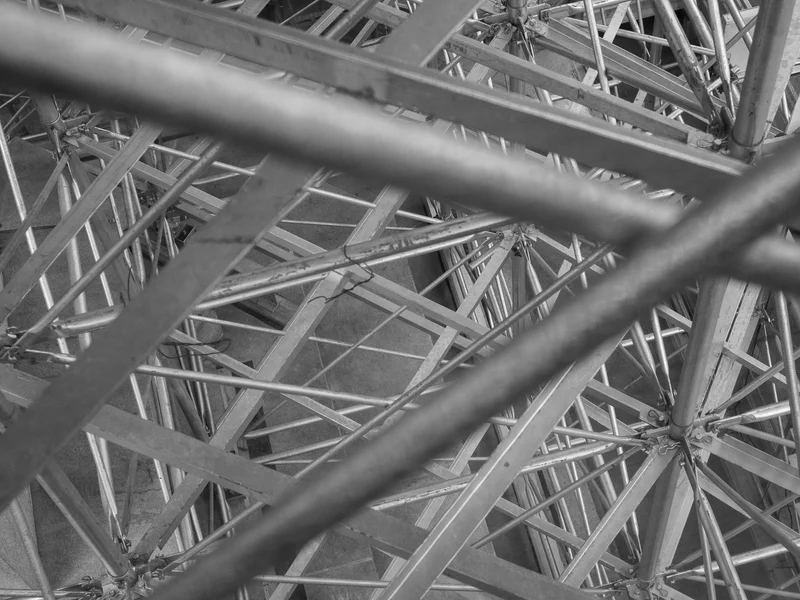 Black and white photograph of an intricate network of intersecting metal beams.