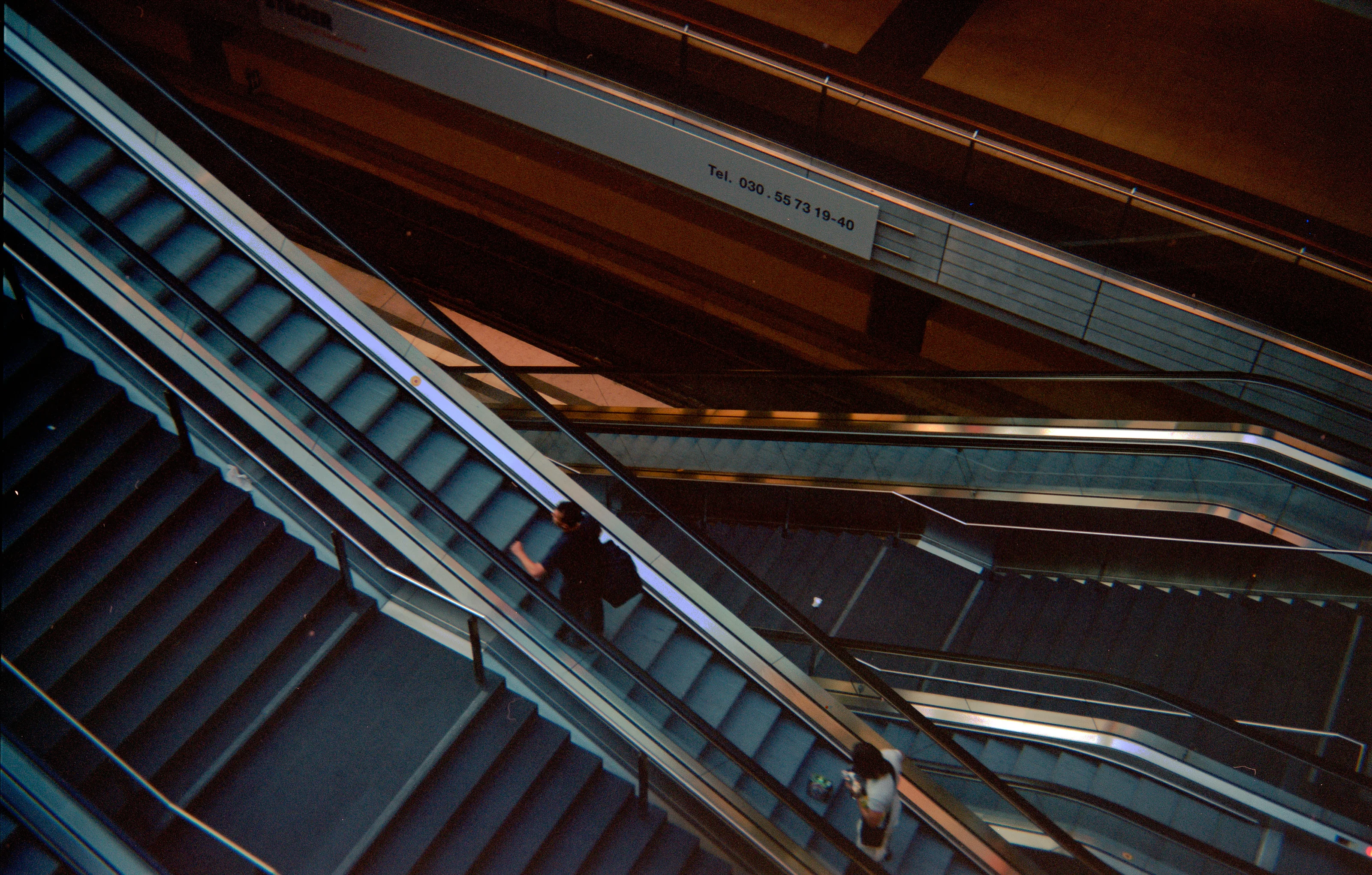 Multiple escalators viewed from above with people ascending and descending.