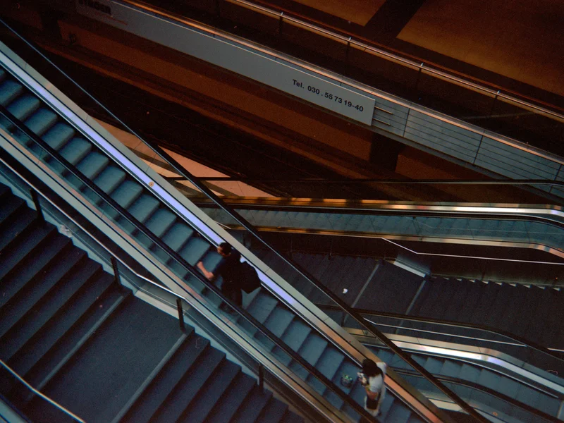 Multiple escalators viewed from above with people ascending and descending.