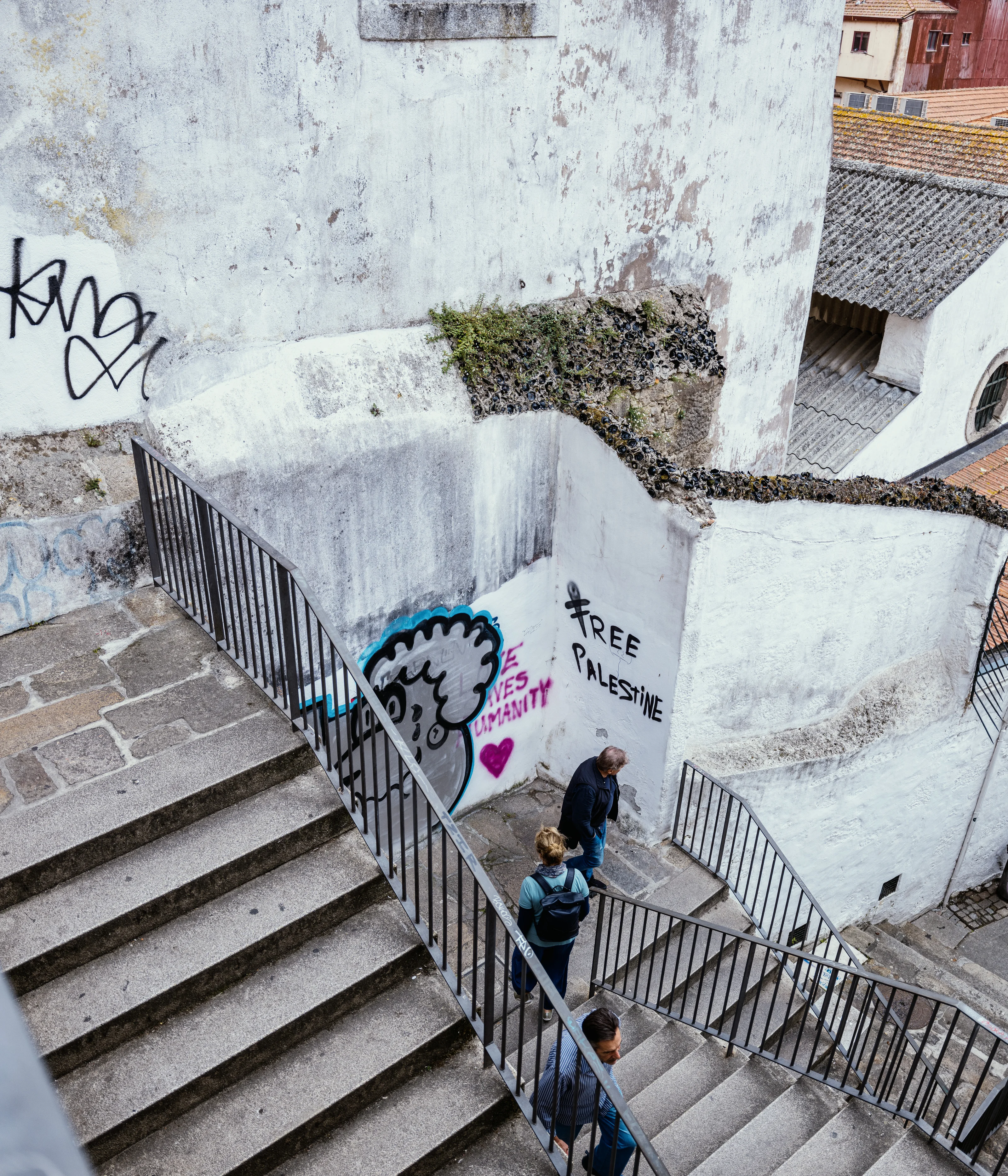 People walking down outdoor stairs with graffiti on the walls in an urban setting.
